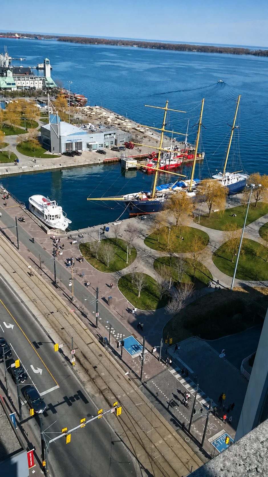Tall ships and tour boats in Toronto inner harbour beside the waterfront promenade