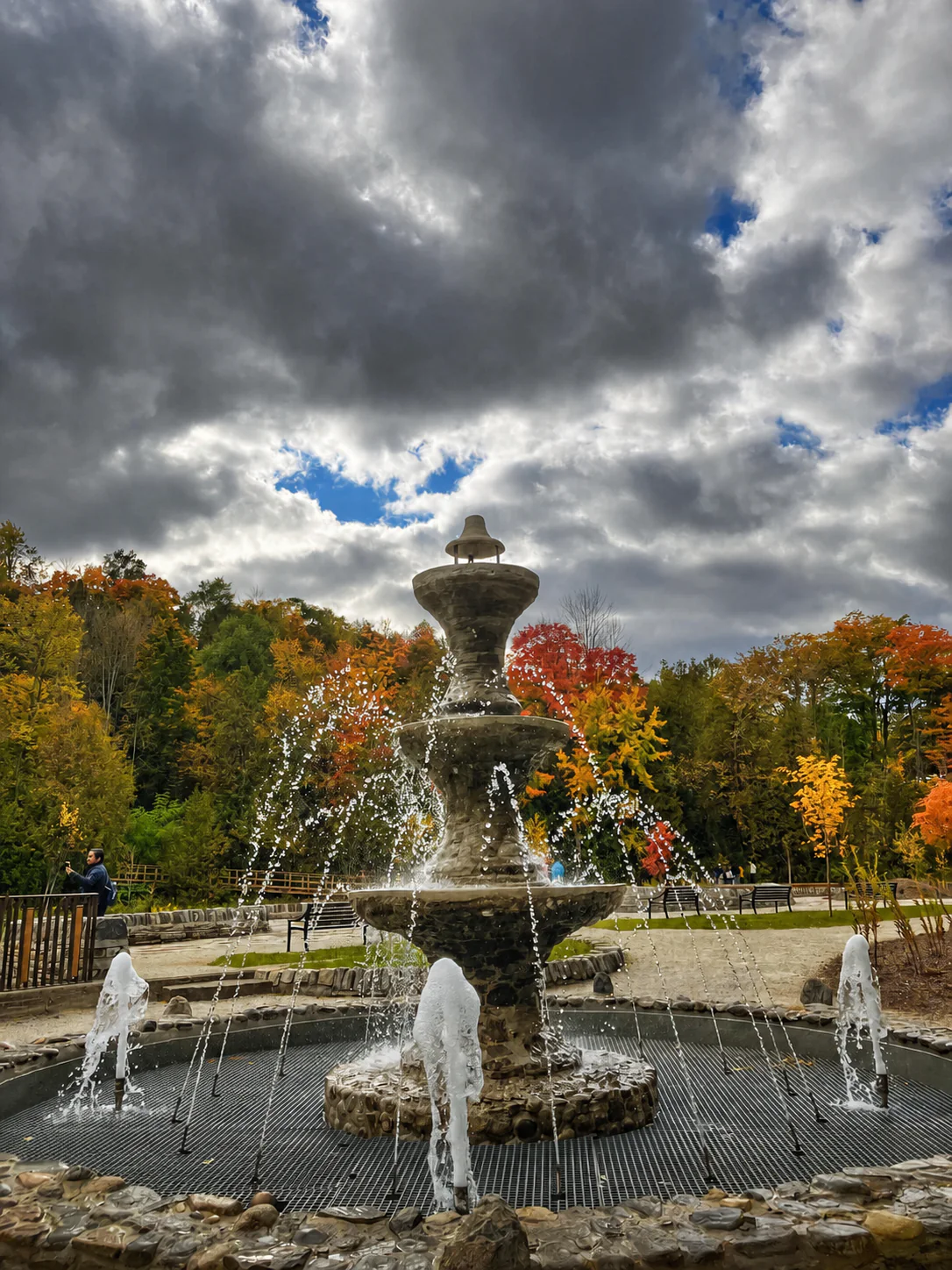 Restored historic belle fountain spraying water in front of autumn trees at Belfountain