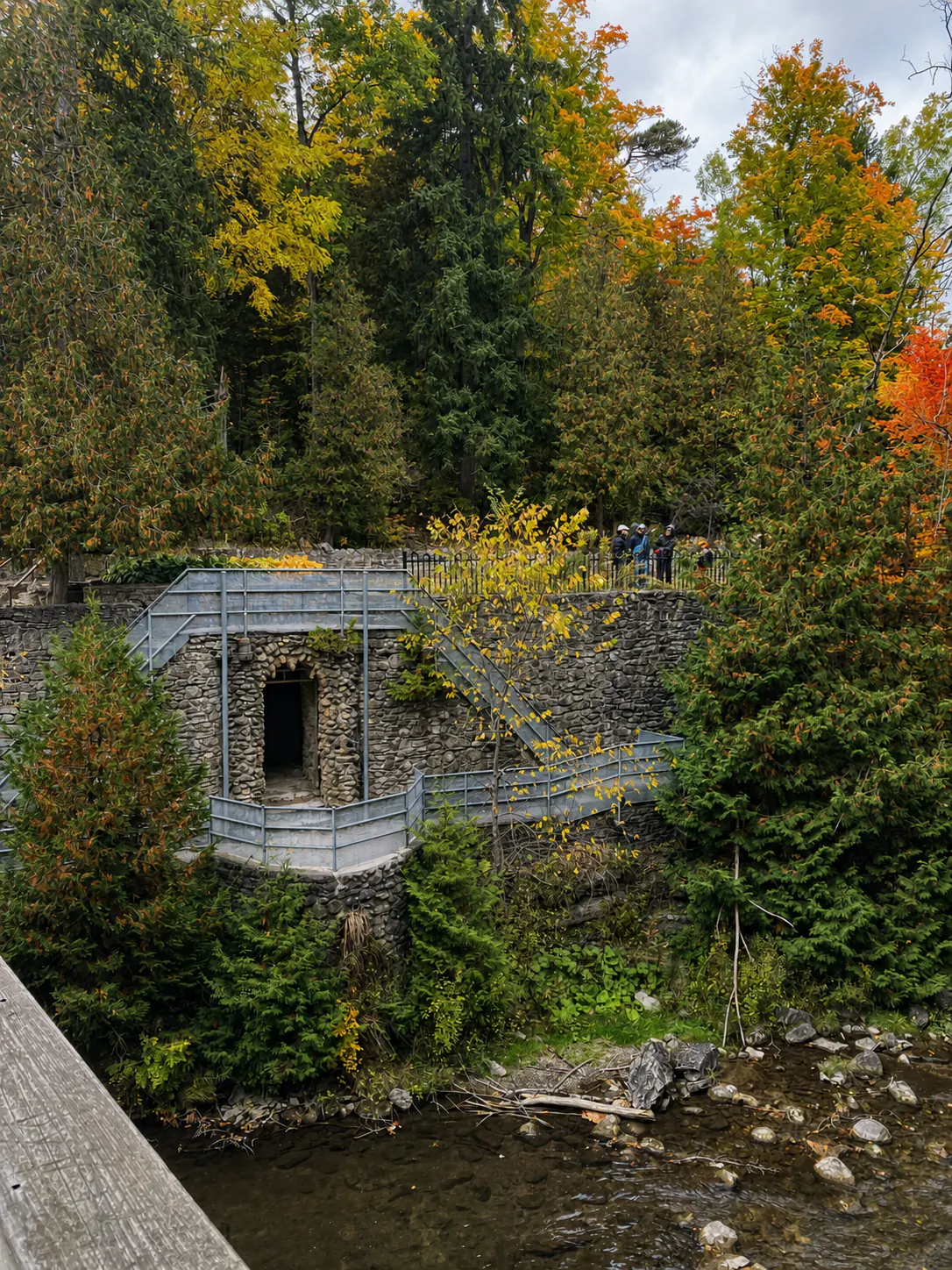 Historic Yellowstone Cave replica with stone walls and metal stairs in Belfountain forest