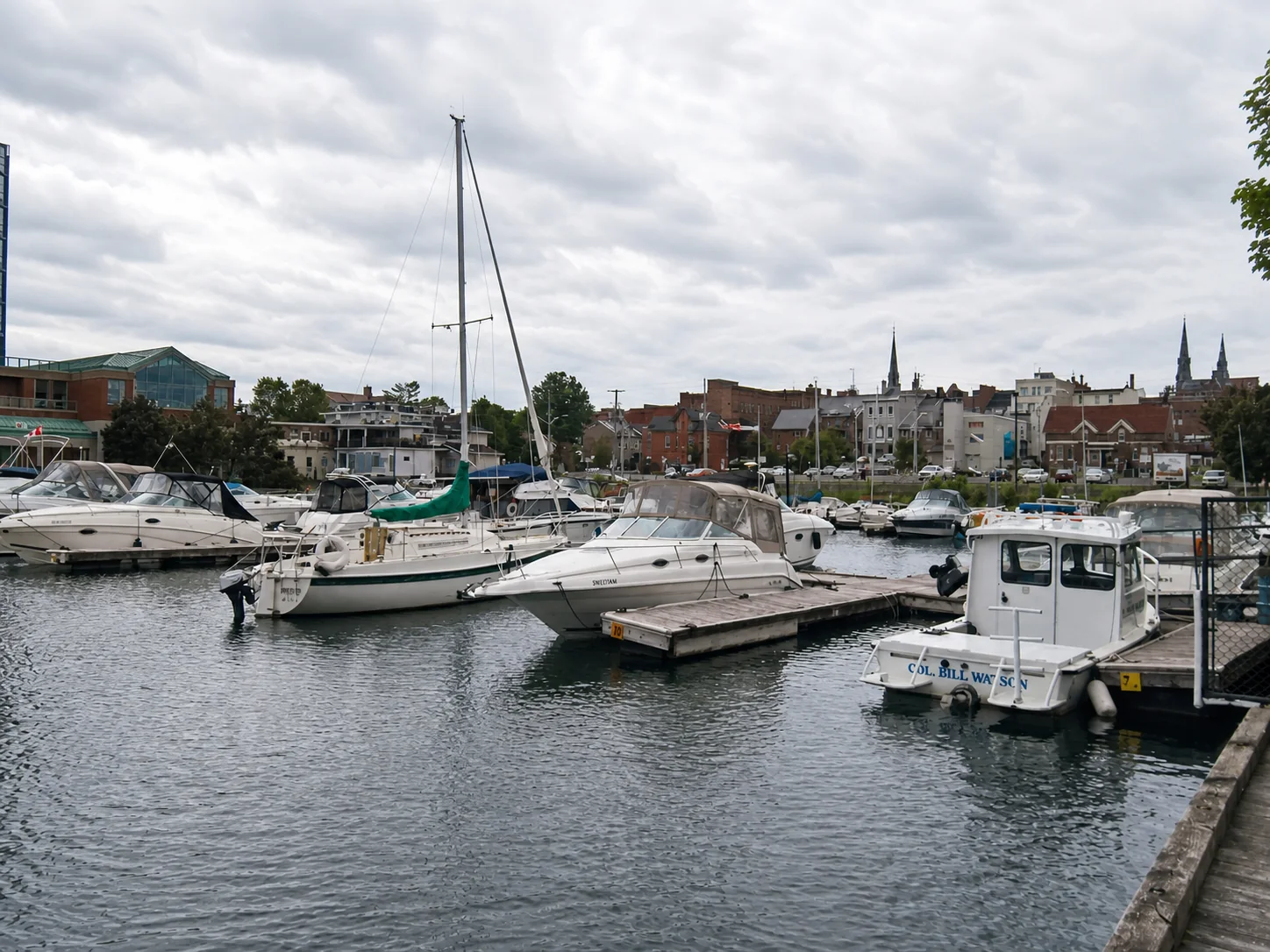 Sailboats and pleasure boats in Brockville municipal harbour with downtown in the background