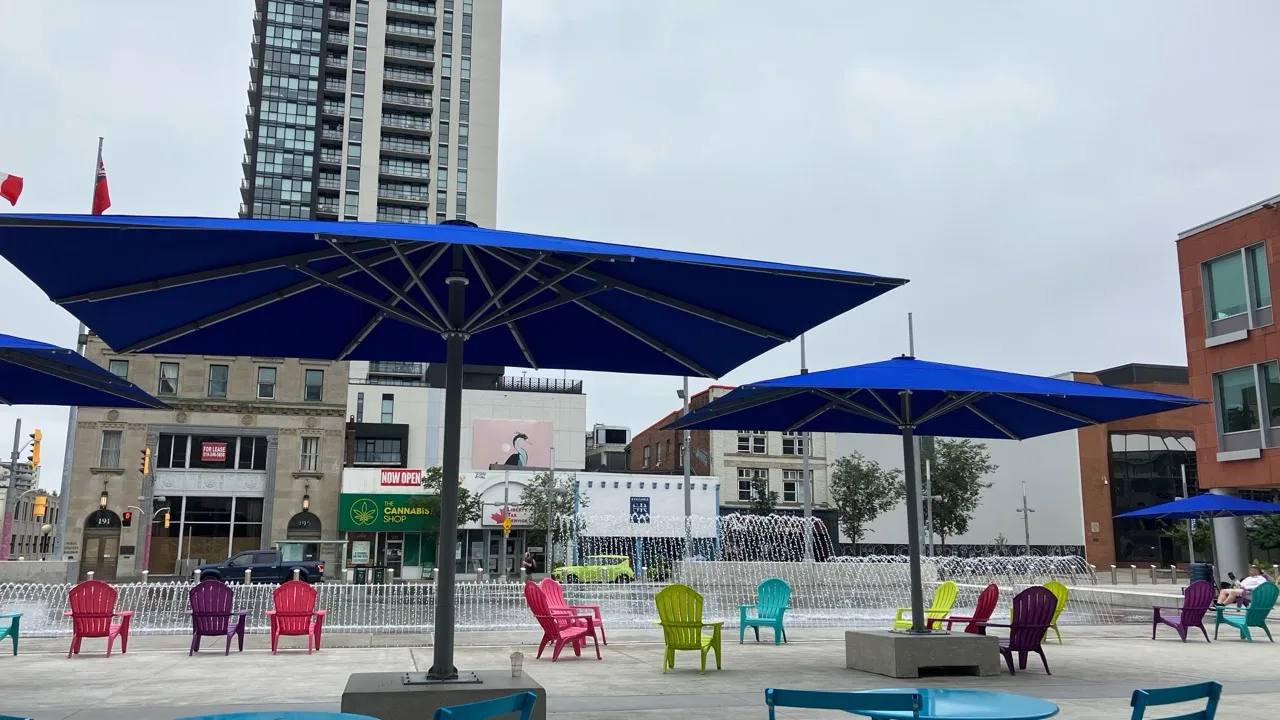 Downtown Kitchener civic plaza with fountains, umbrellas, and colourful chairs