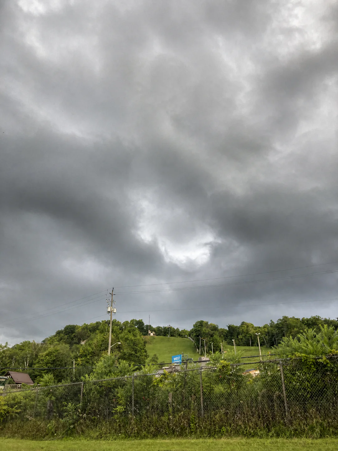 Green Glen Eden ski hill below dark summer storm clouds near Milton Ontario