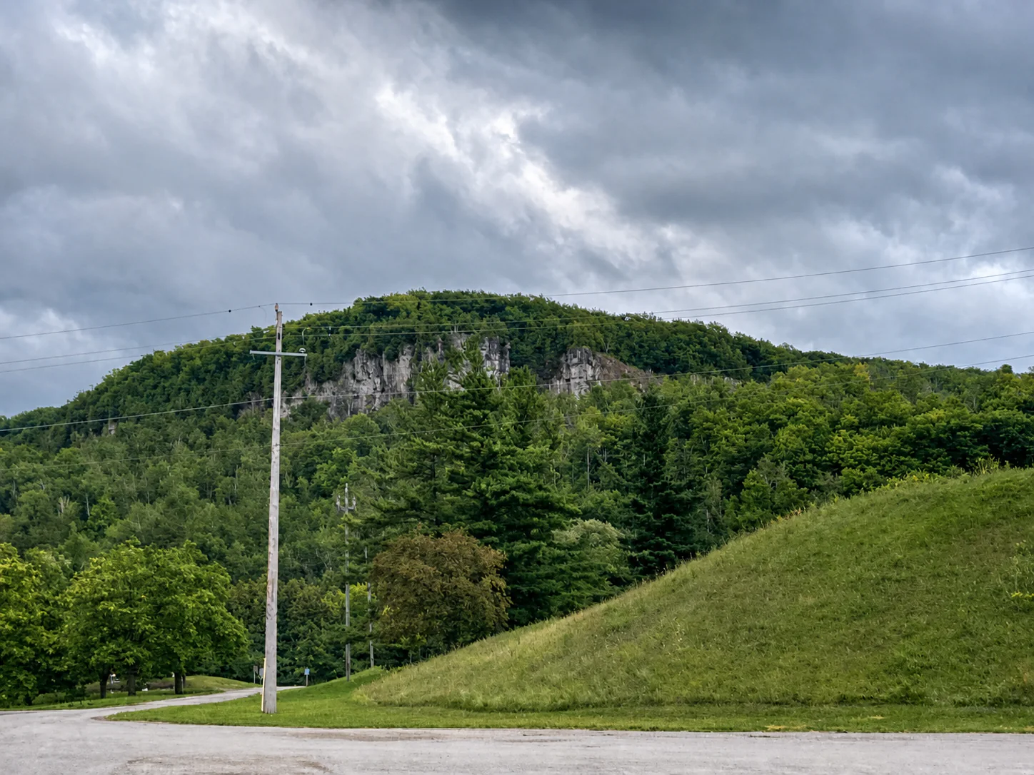 Exposed Niagara Escarpment rock and green forest rising beside Kelso Conservation Area