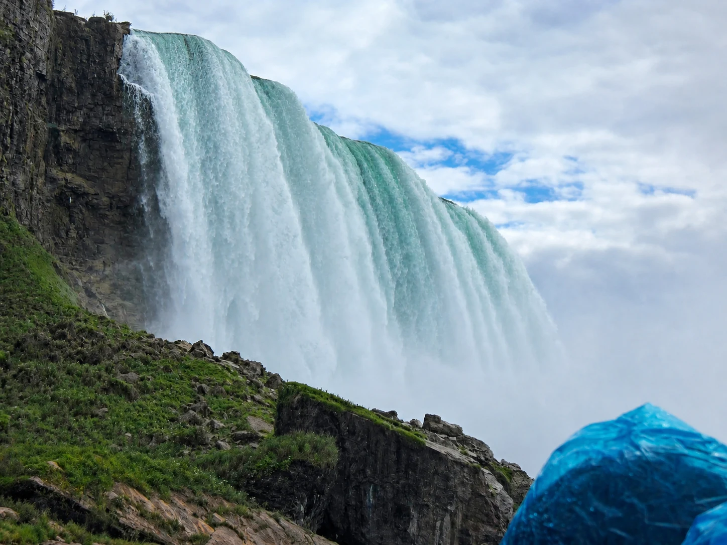Horseshoe Falls filling the frame beside a blue poncho