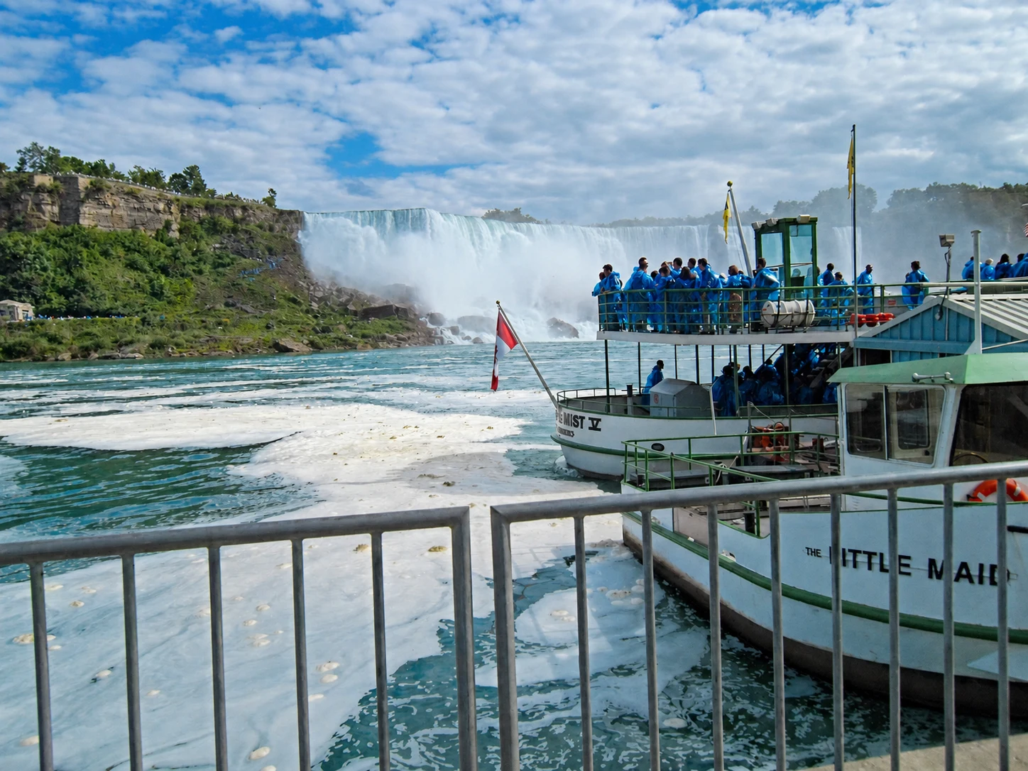 Historic Little Maid landing and blue-poncho passengers near the falls