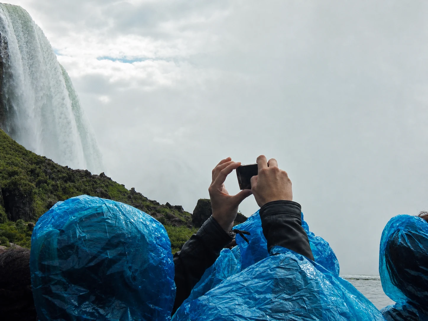 Blue ponchos and a camera in the spray at the base of the falls
