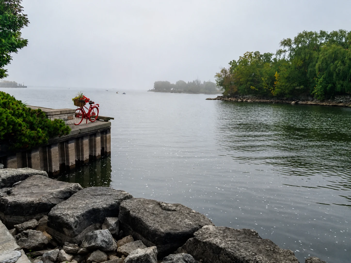 Red bicycle sculpture beside a misty Port Credit waterfront