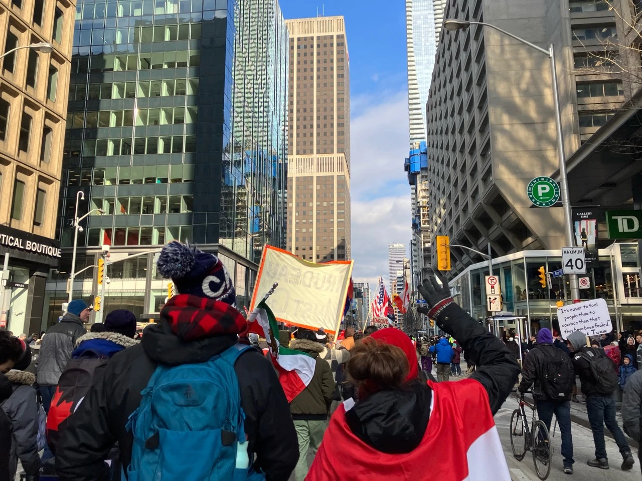 Political march moving along a downtown Toronto street with flags and winter clothing