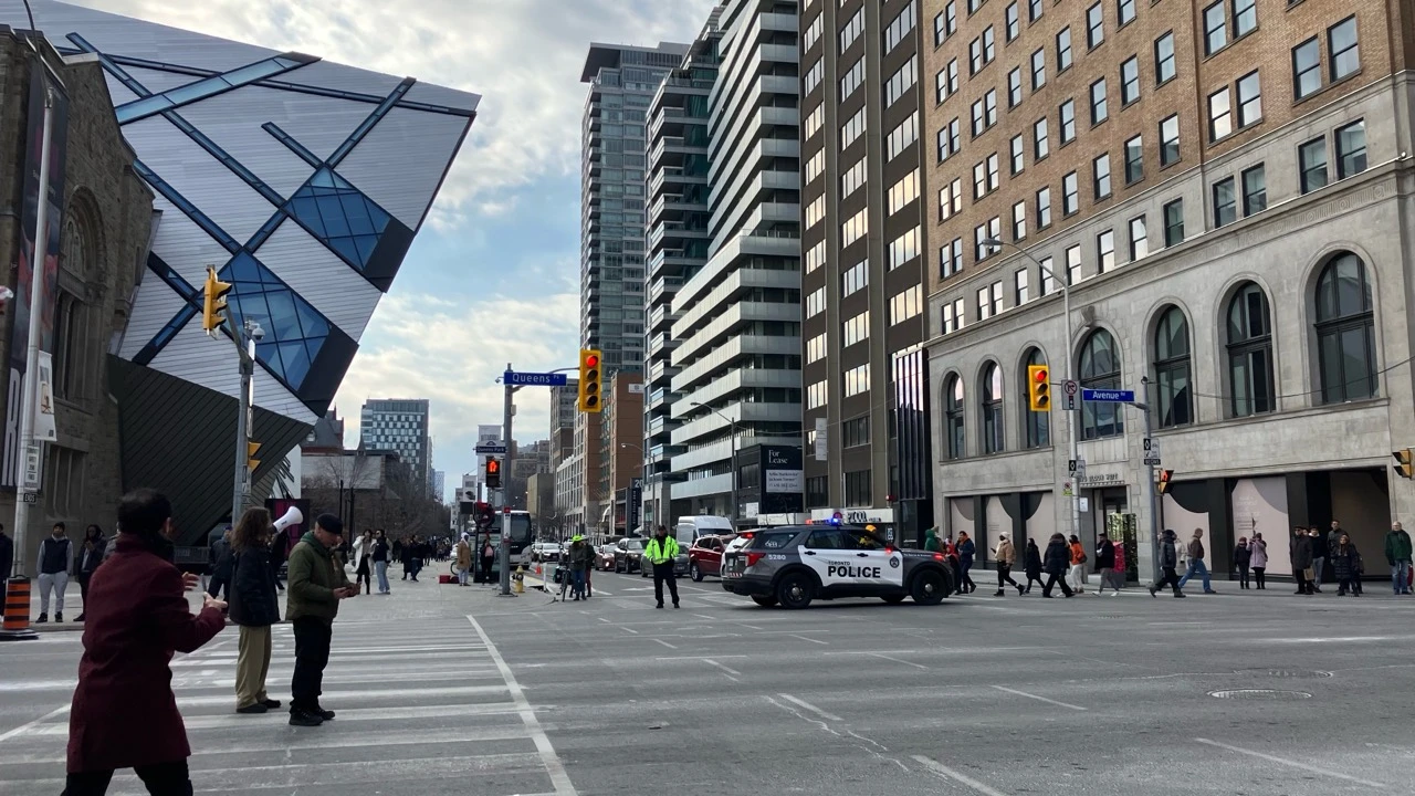 Toronto Police vehicles and officers managing a temporary road closure near Queen's Park and the ROM