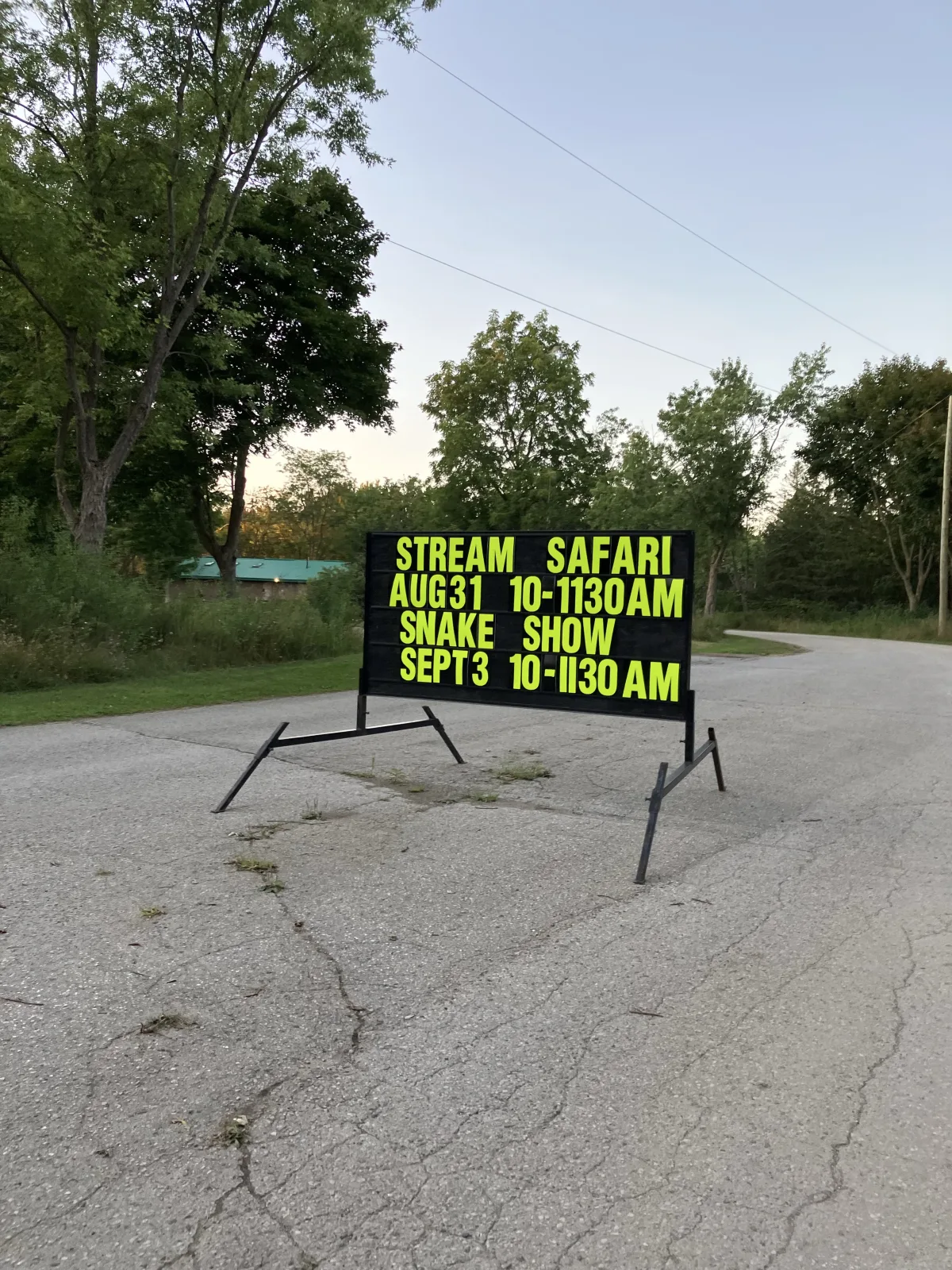 Past Wildwood Conservation Area sign advertising a stream safari and snake show